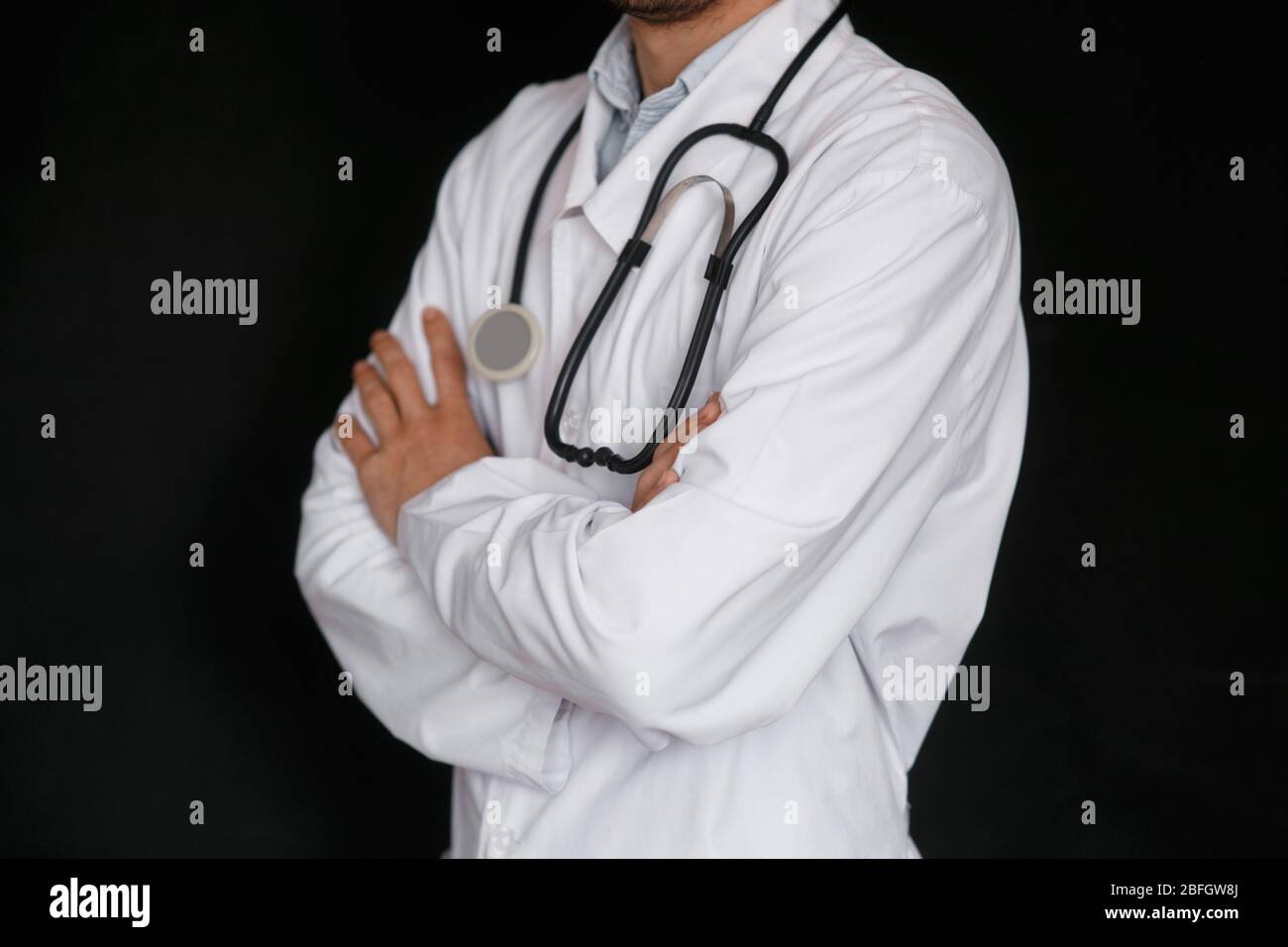 Male Doctor on a black background with a stethoscope in his hands close-up. Stock Photo