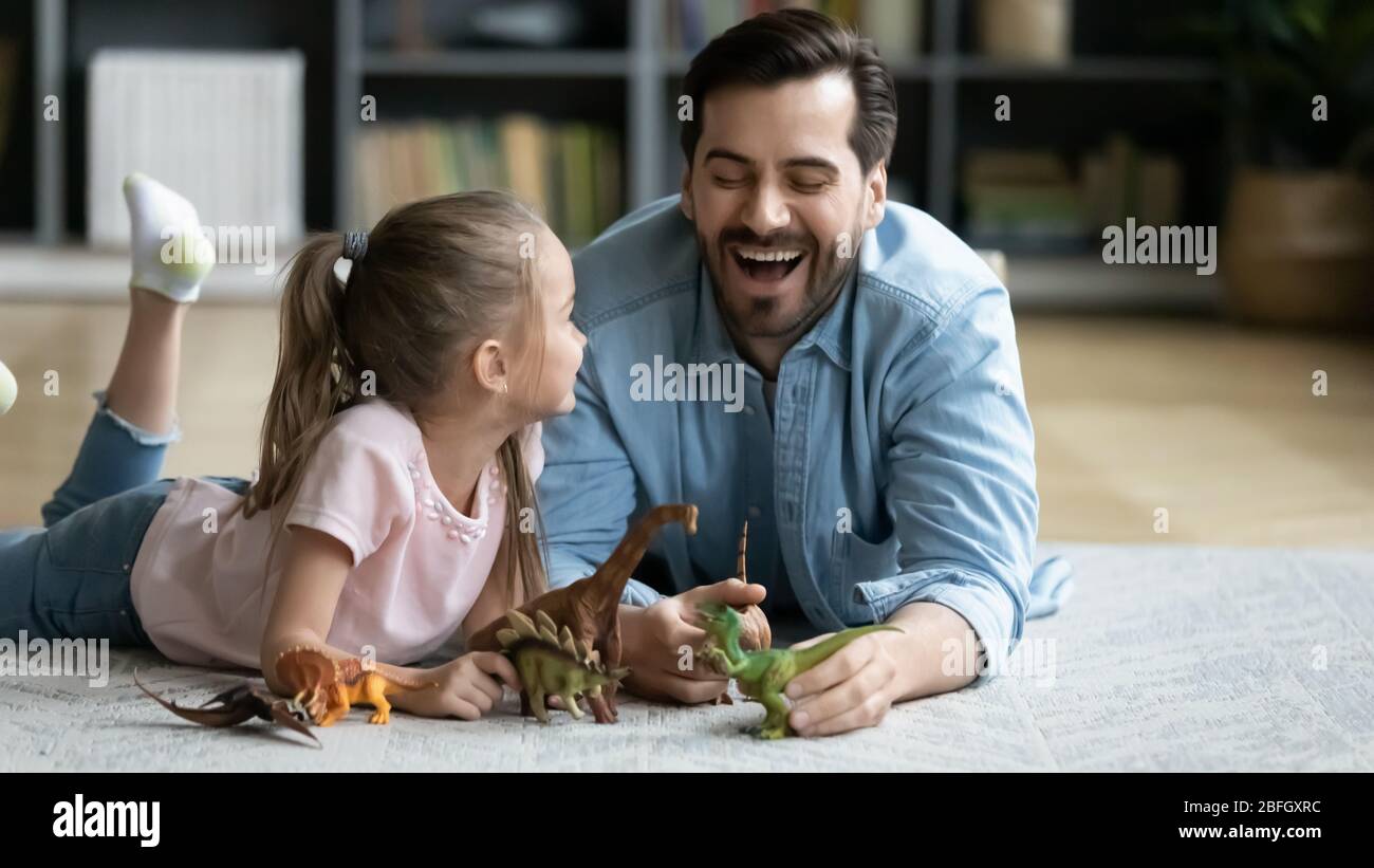 Father having fun with little daughter play with dinosaurs toys Stock Photo