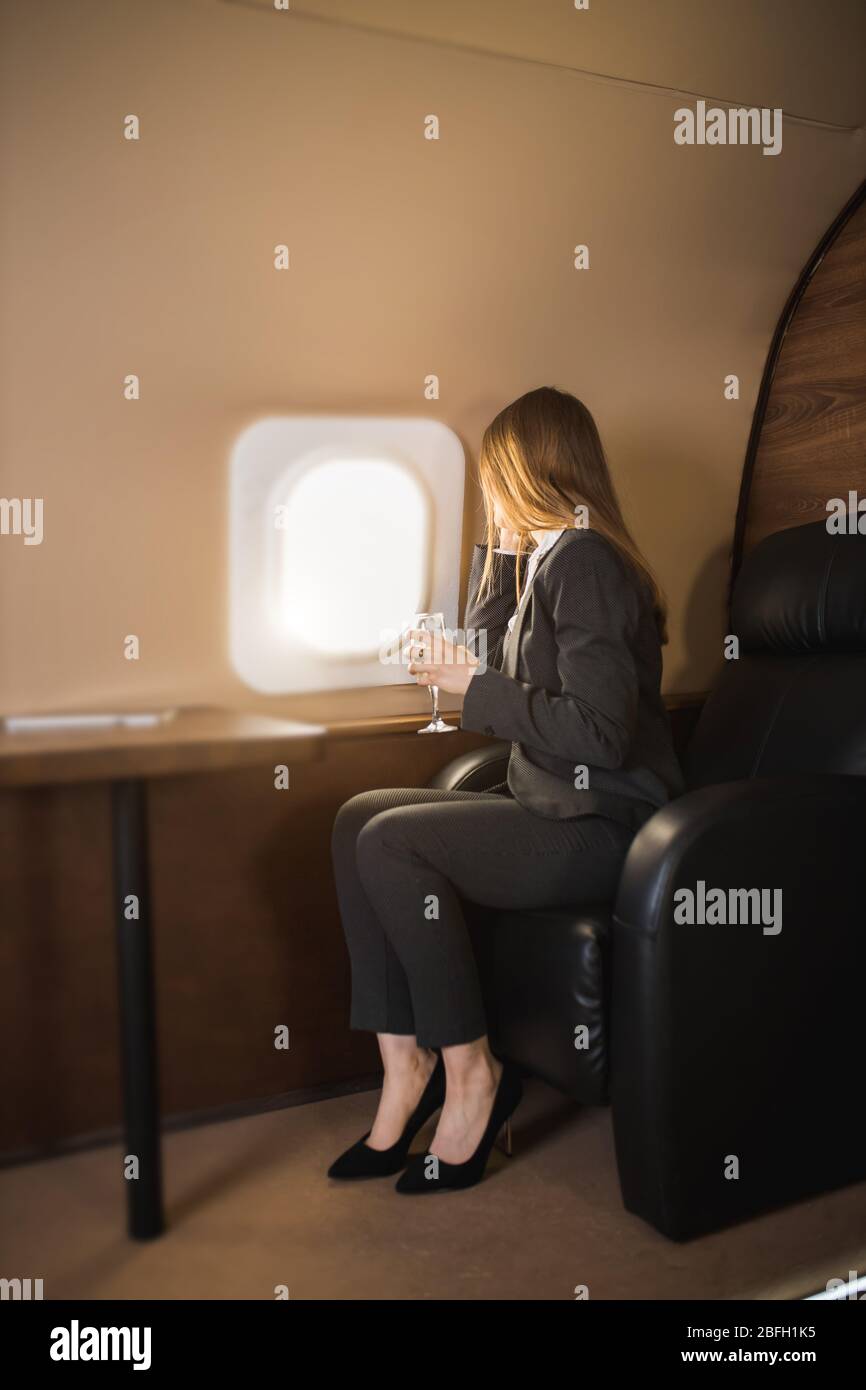 Side view of caucasian woman with long brown hair, wearing black suit