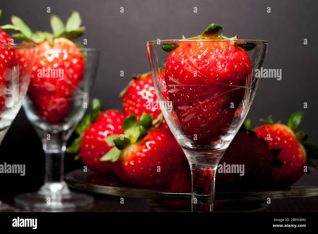 close-up of many strawberry fruit in a little decorated glass and on a plate Stock Photo