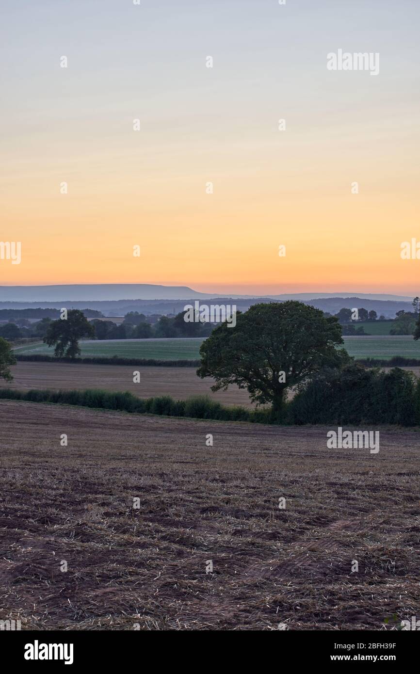 Cut wheat field in Herefordshire countryside with bails towards Hay Fluff at sunset Stock Photo