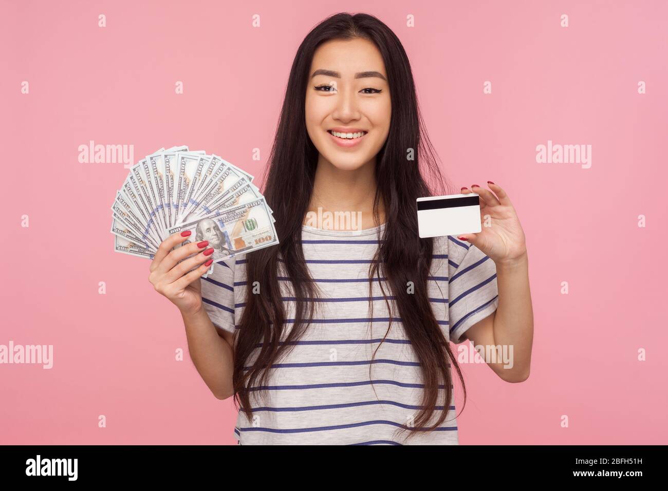Cash deposits. Portrait of satisfied bank customer, happy brunette girl holding dollars banknotes, credit card and looking at camera with toothy smile Stock Photo