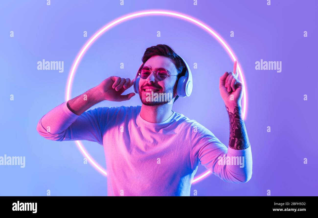 Guy dances to favorite music in neon circle Stock Photo