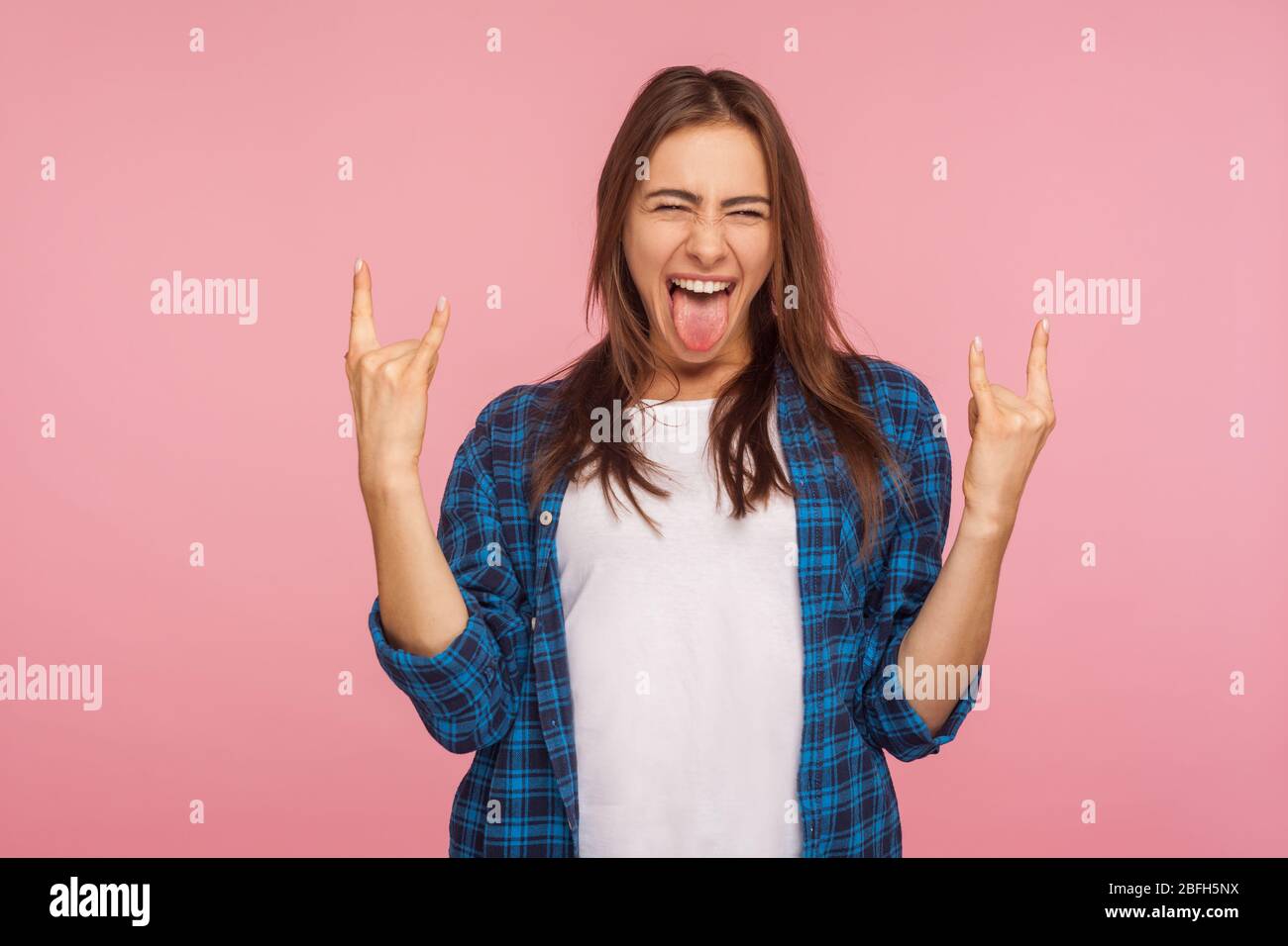 Portrait of enthusiastic crazy girl in checkered shirt showing rock and ...