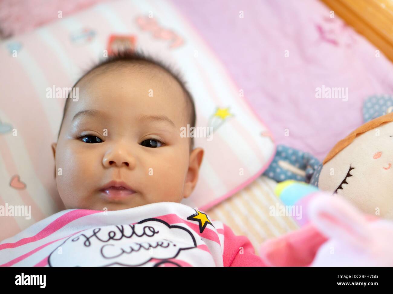 A 6 month old Asian girl is smiling and looking at his mother. Stock Photo