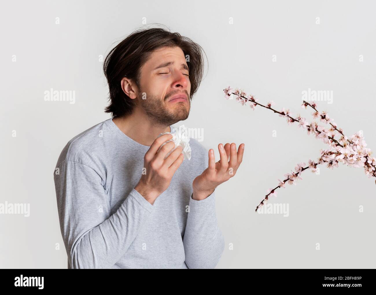 Man smelling flowers and suffer from allergies Stock Photo