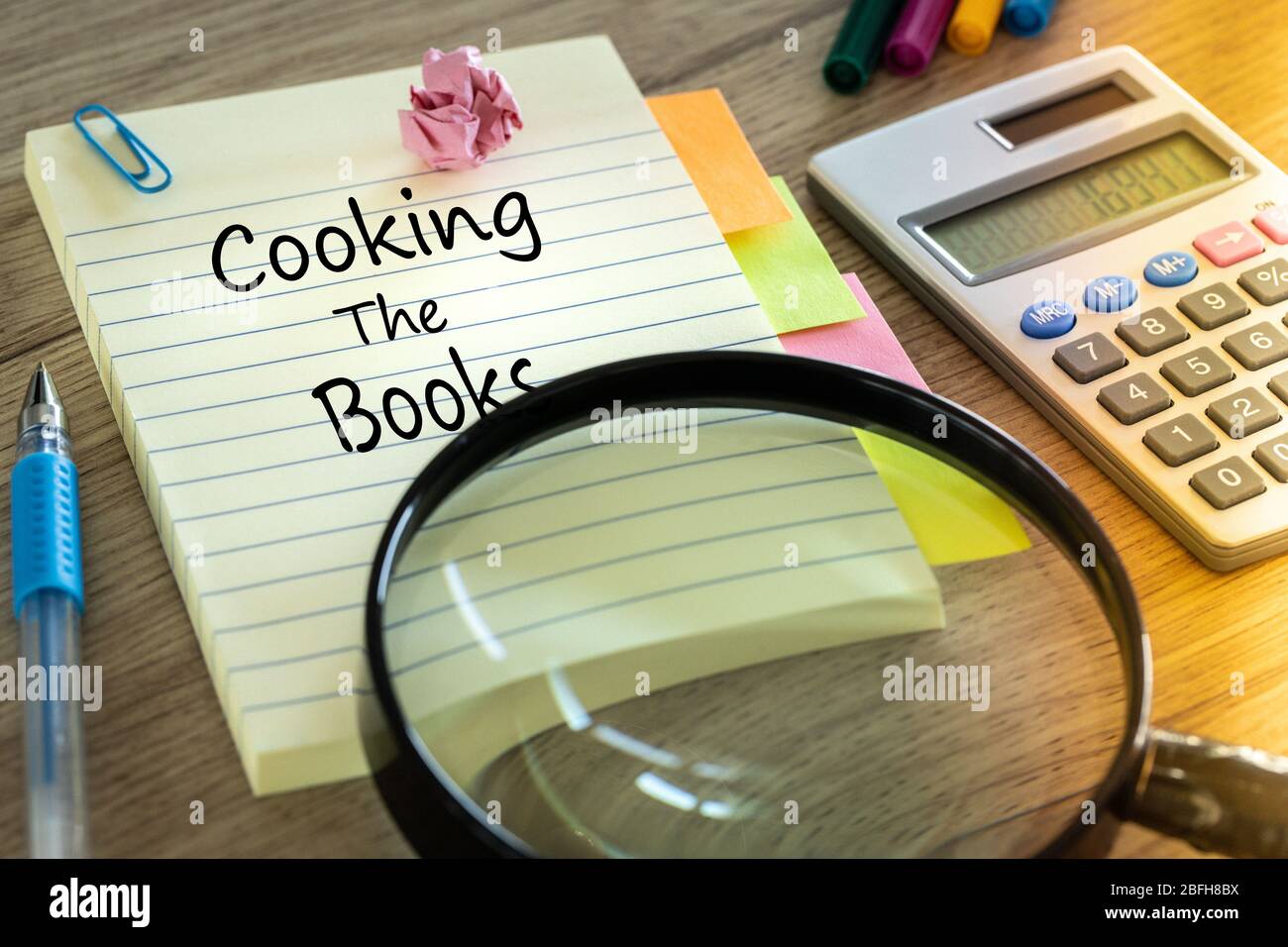 Notebook with the words "Cooking the books" Creative accounting concept. Calculator, office accessories, magnifying glass Stock Photo