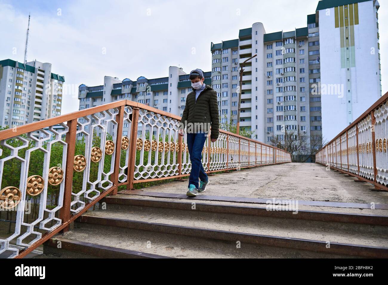 View of teen boy walks down the street during the day, a pedestrian walkway and ...