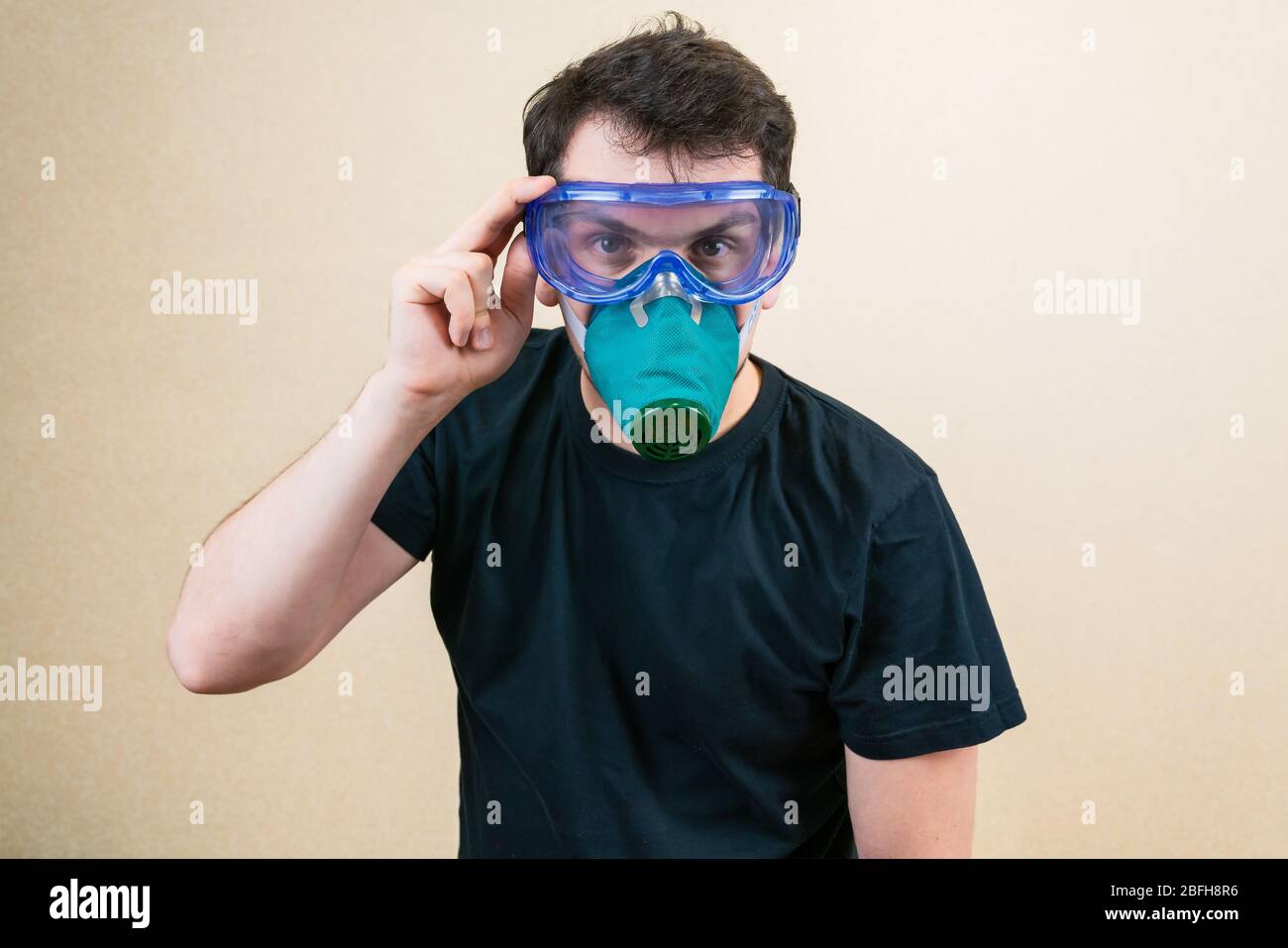 Young man in protective respirator mask and glasses during self-isolation and quarantine. Stay home Stock Photo