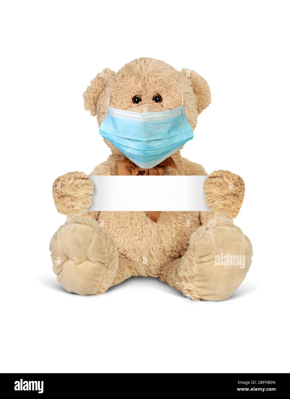Toy bear wearing mask, hold empty blank, isolated on white. Covid-19 and protect from epidemic concept Stock Photo