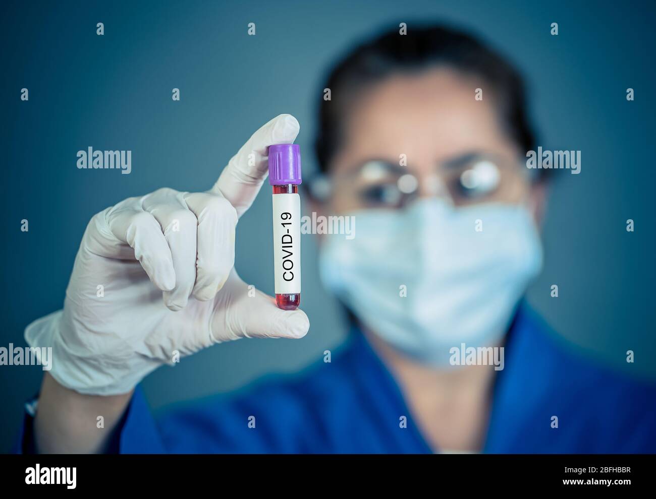 COVID-19. Doctor or lab technician scientist in Personal Protective Equipment holding vial of blood sample of infected patient at hospital. Coronaviru Stock Photo