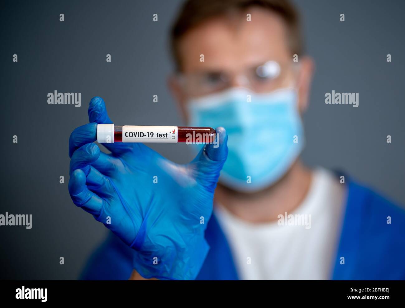COVID-19. Doctor scientist in Personal Protective Equipment holding vial of blood sample test of infected patient at lab hospital. Coronavirus blood t Stock Photo
