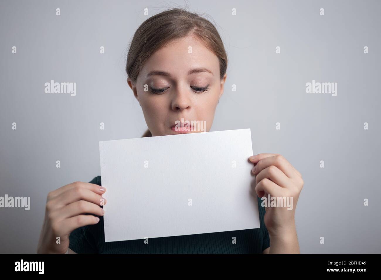 Smiling young Caucasian woman girl holding blank white paper sheet with copy space Stock Photo
