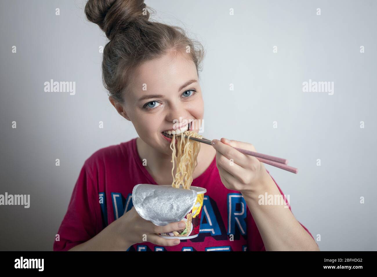 Young caucasian girl woman eating instant noodles ramen with chopsticks Stock Photo