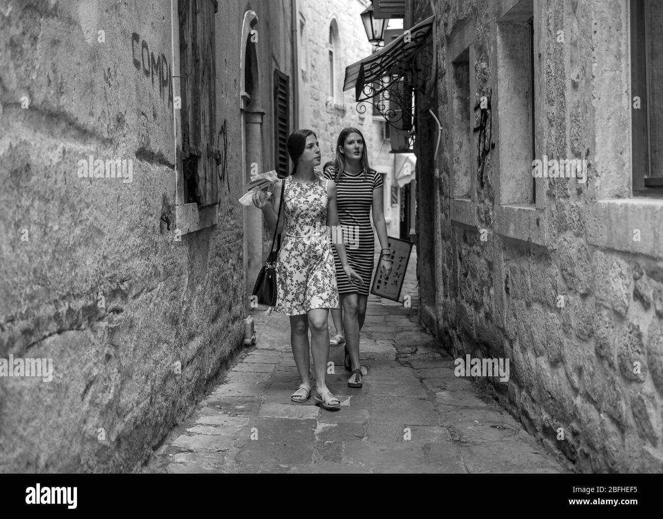 Montenegro, Sep 17, 2019: Two young women walking and snacking down the narrow cobblestone street of Kotor Old Town Stock Photo