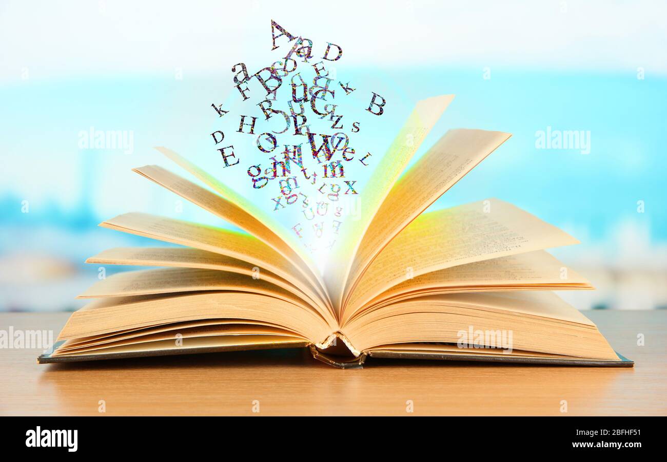 Open book with letters on bright background Stock Photo - Alamy