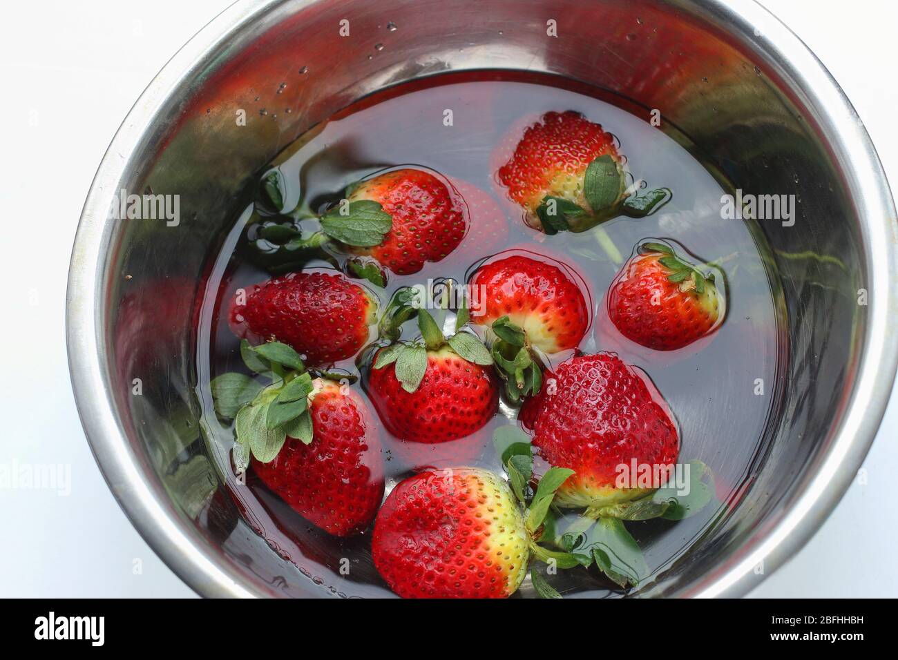 Soaking fresh strawberries in stainless steel bowl isolated on white background Stock Photo