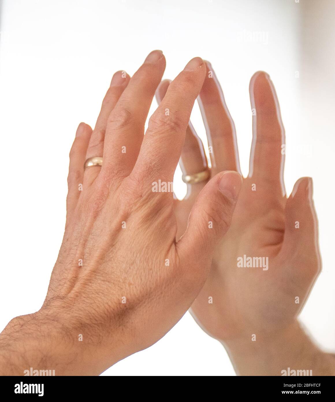 white hand touching itself in a mirror showing reflection Stock Photo