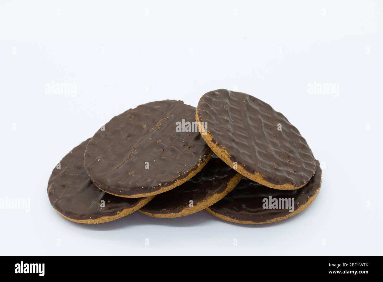 Five chocolate digestive biscuits in a pile on a white background. An