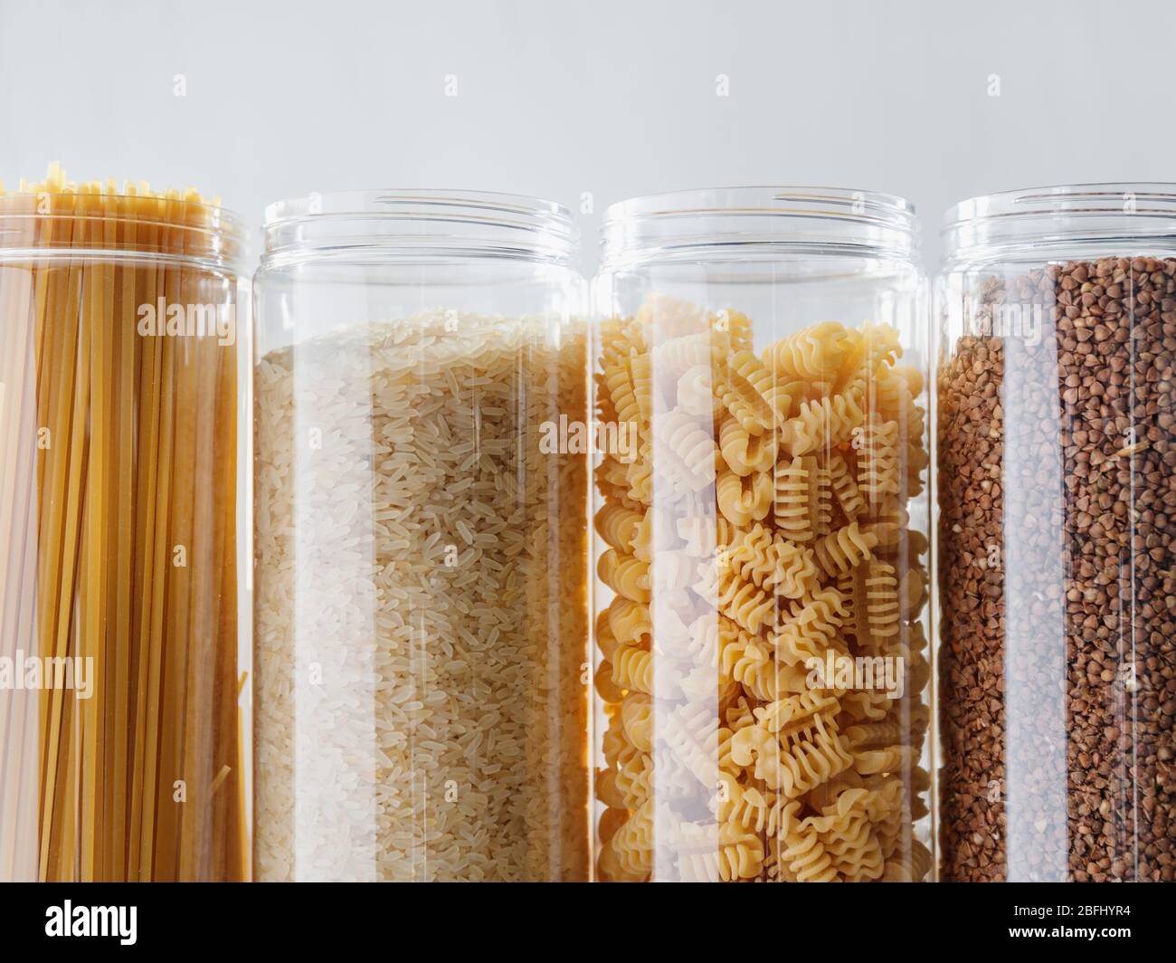 Various pasta and cereal grains in plastic jars for a long storage. Stock Photo