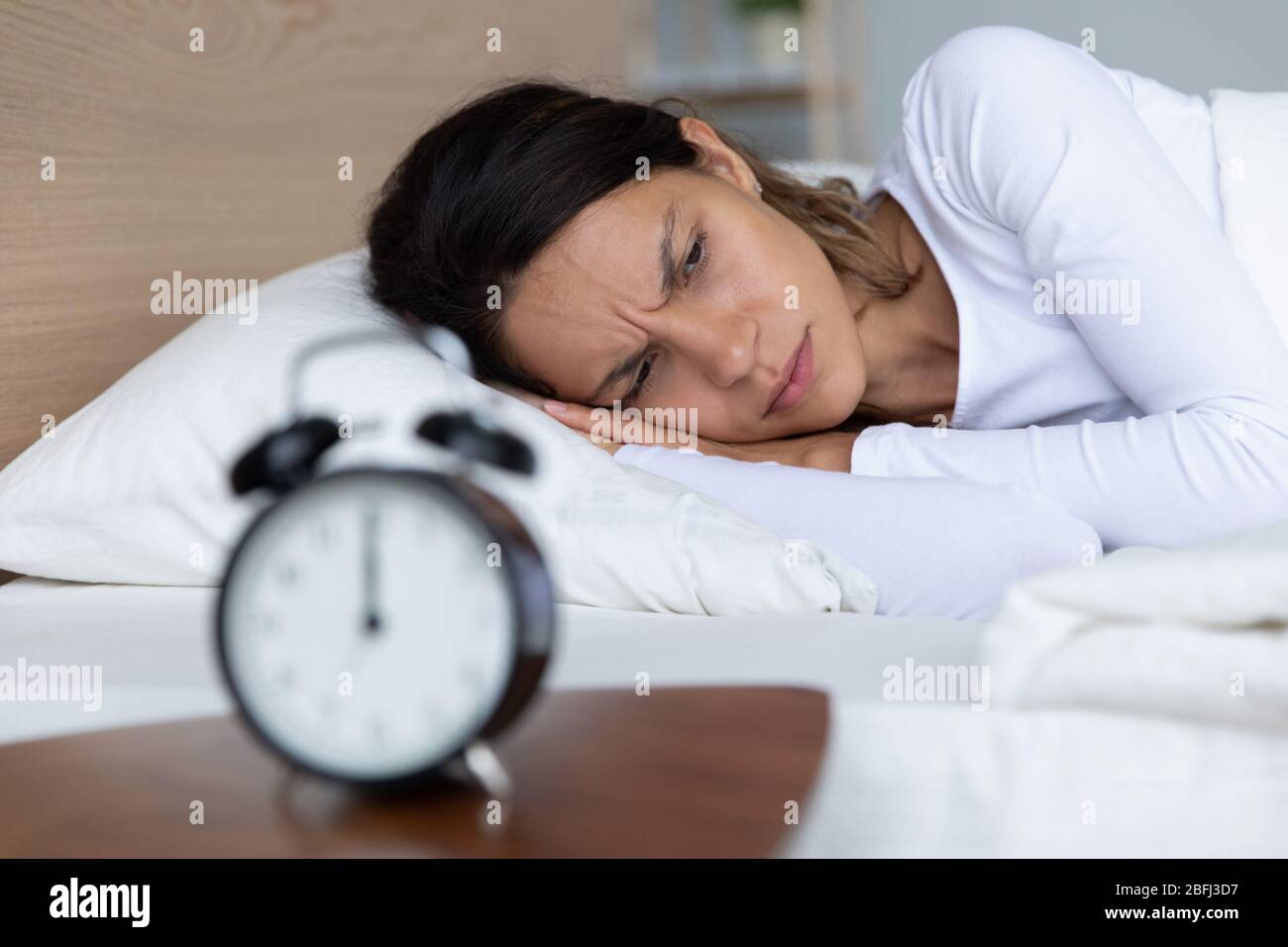 Unhappy restless woman lying in bed, suffering from insomnia Stock Photo