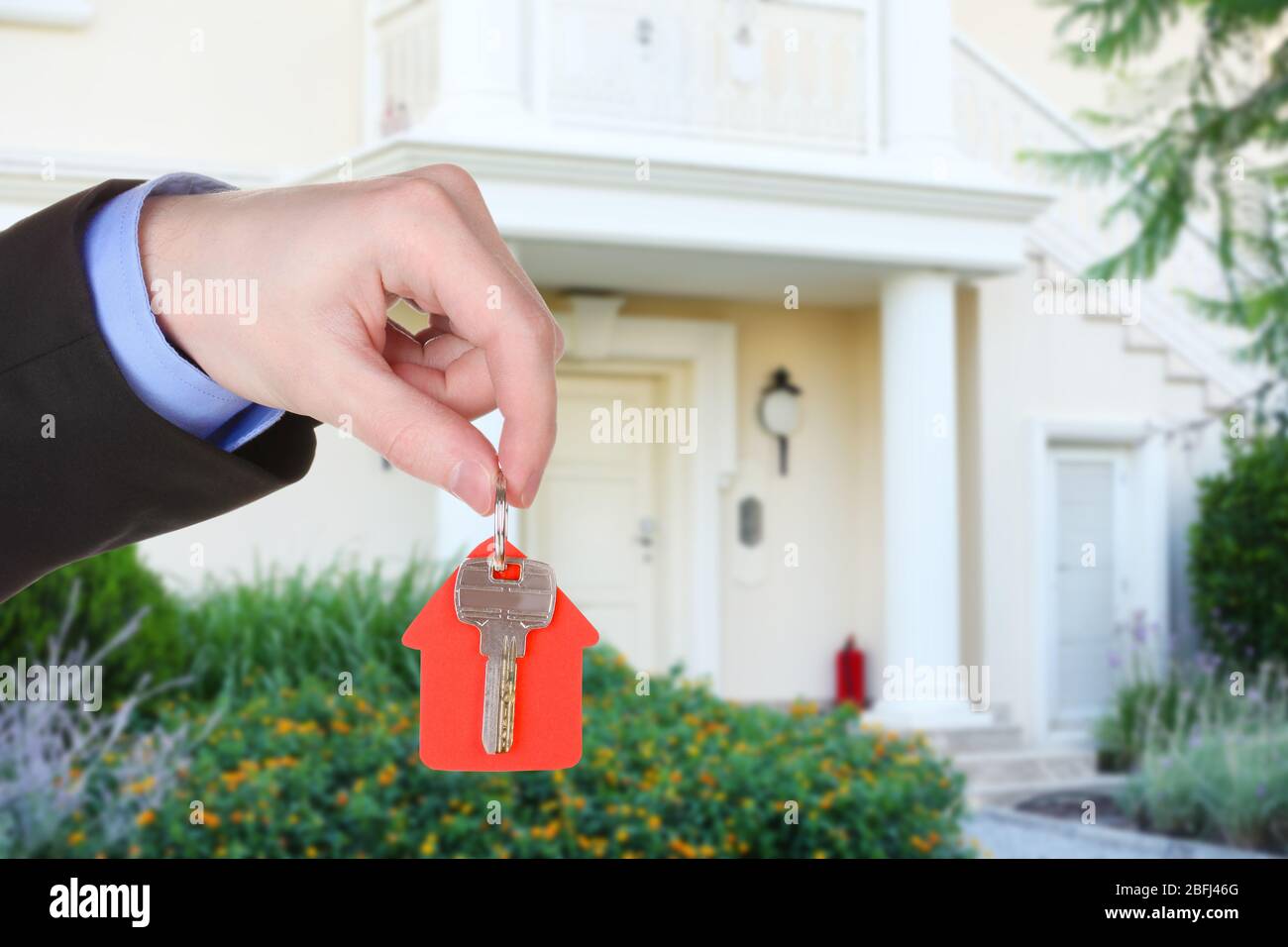 Key in hand on house background, Real estate concept Stock Photo - Alamy