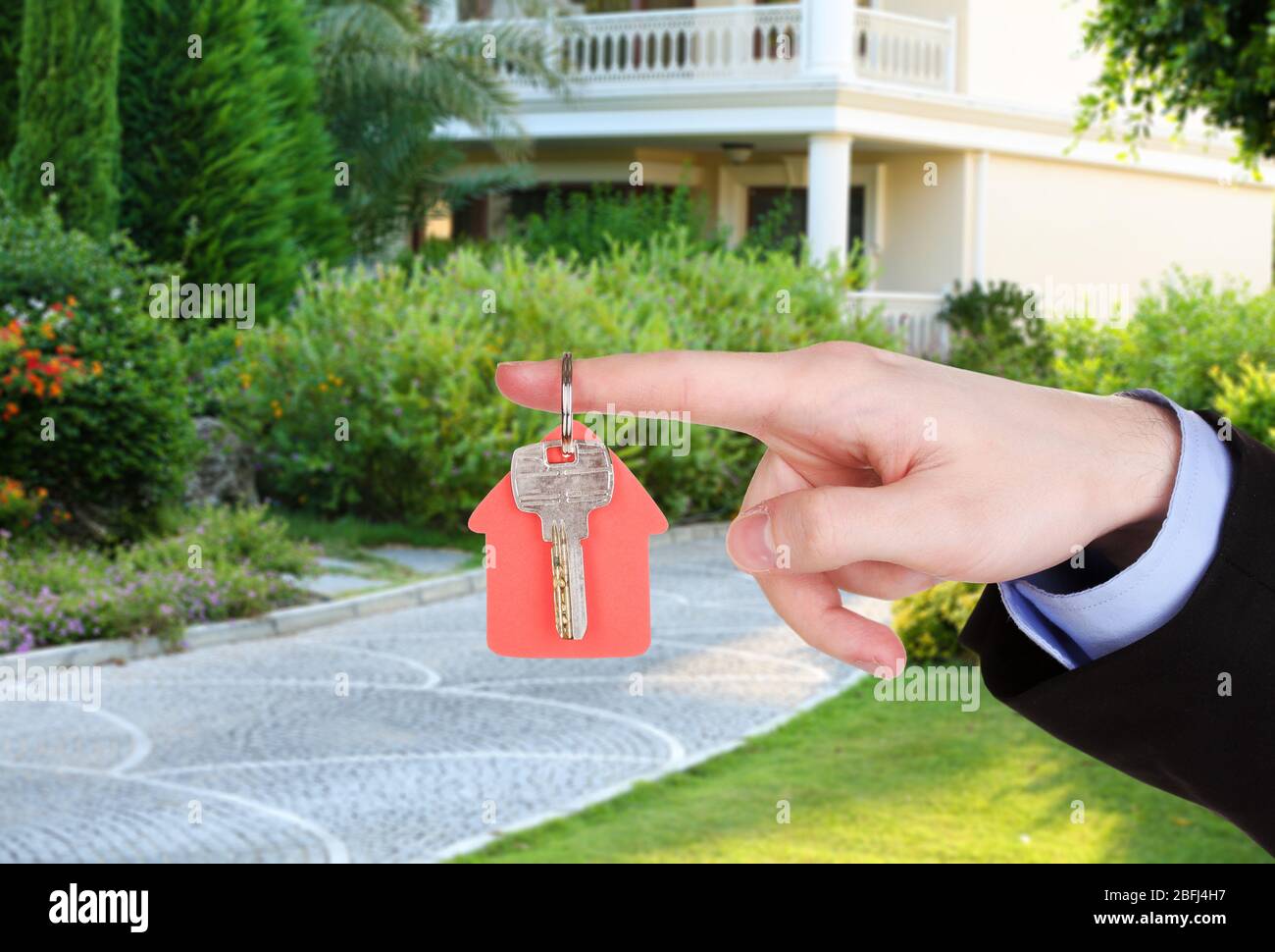 Key in hand on house background, Real estate concept Stock Photo - Alamy