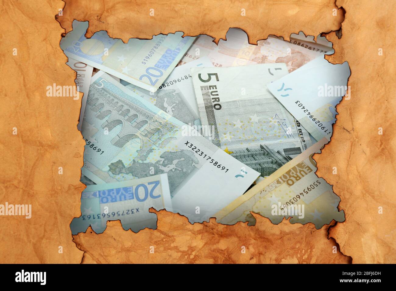 Euro banknotes through torn craft paper Stock Photo