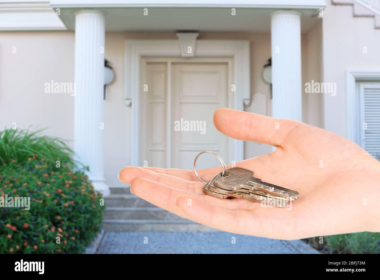 Key in hand on house background, Real estate concept Stock Photo - Alamy