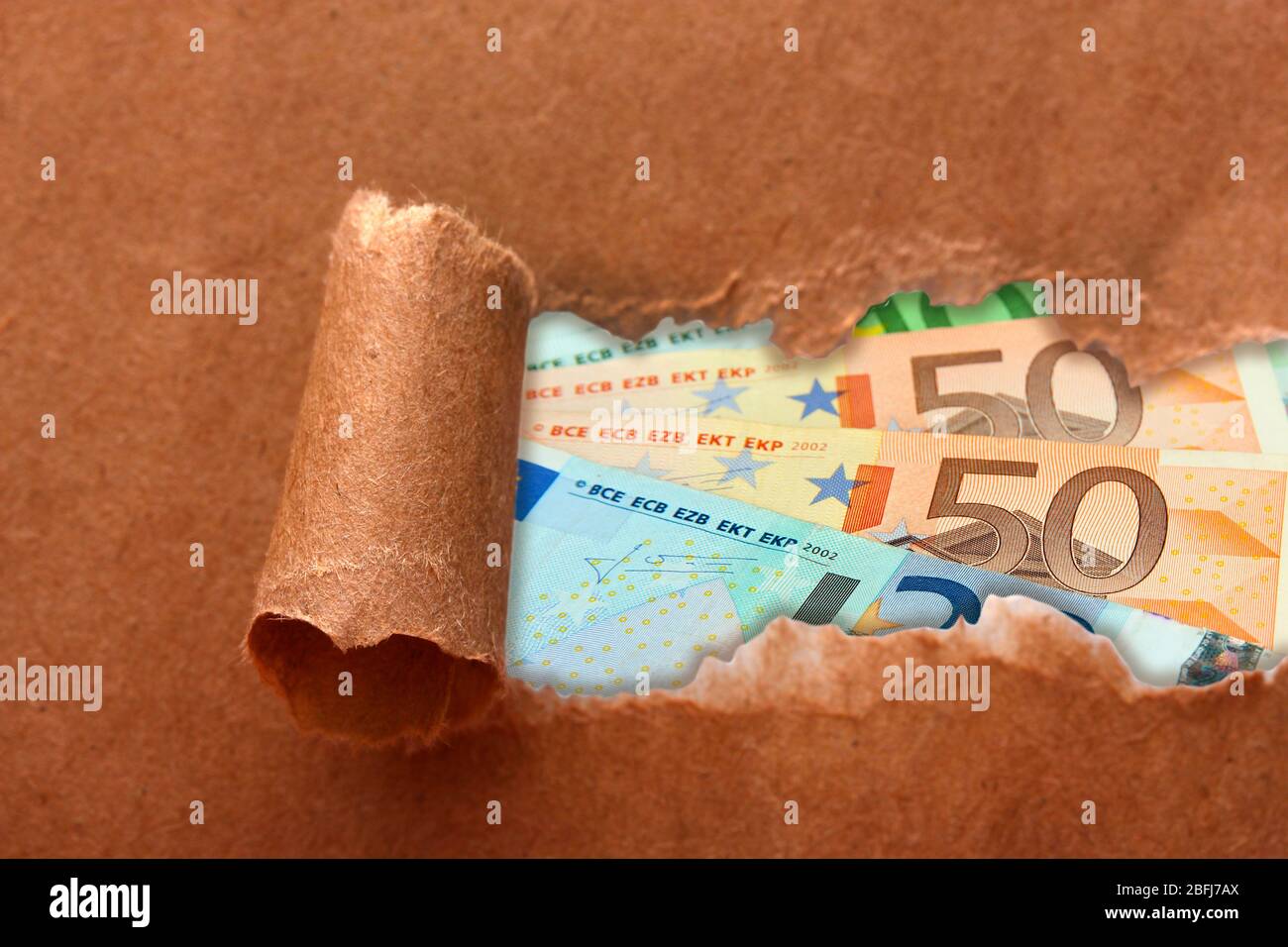 Euro banknotes through torn craft paper Stock Photo