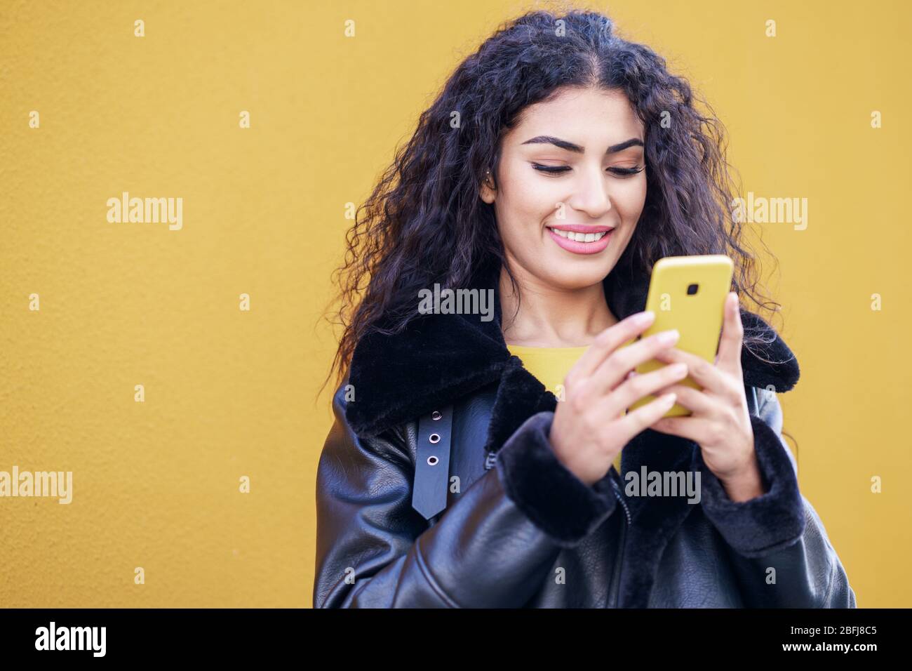Young Arab woman walking in the street using her smartphone Stock Photo ...
