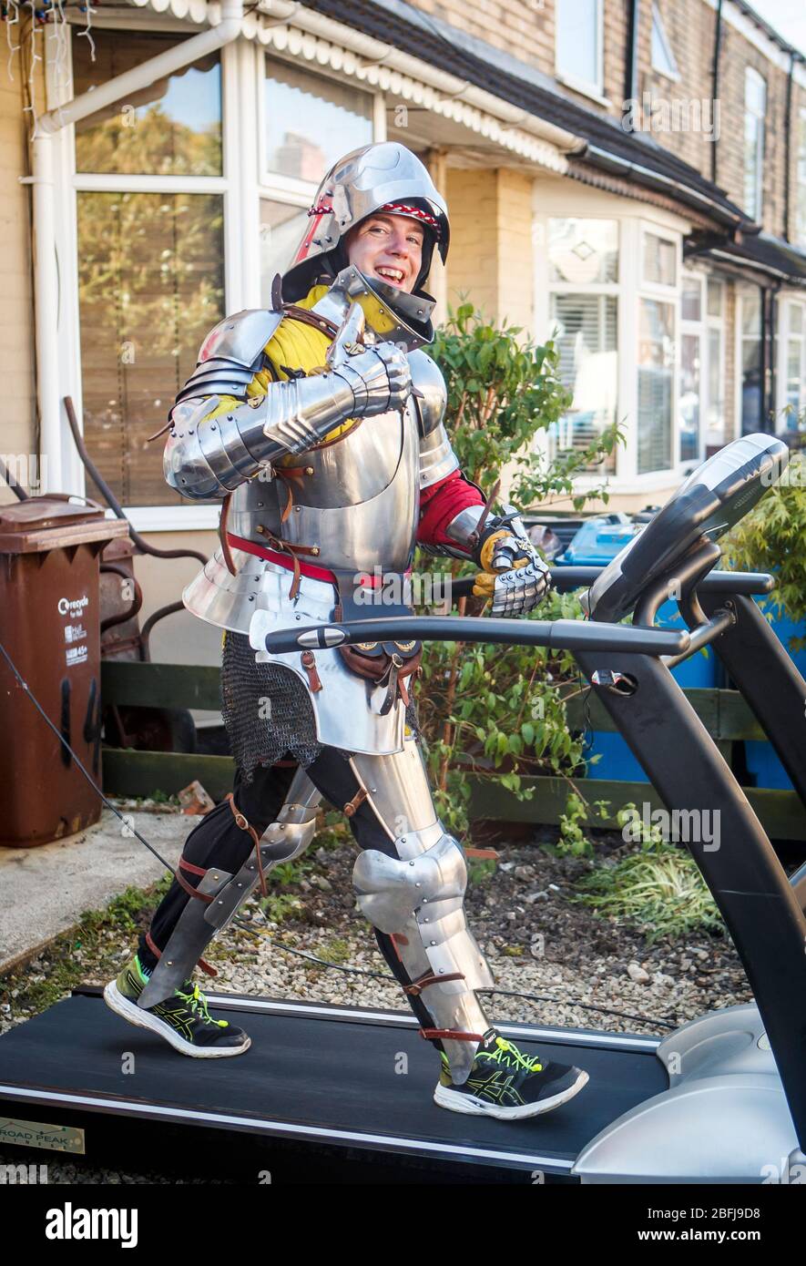 Mike Manders, 34, uses a treadmill in his front garden in Hull, dressed in a suit of armour as he attempts the postponed Hull 10k, whilst the UK continues in lockdown to help curb the spread of the coronavirus. Stock Photo