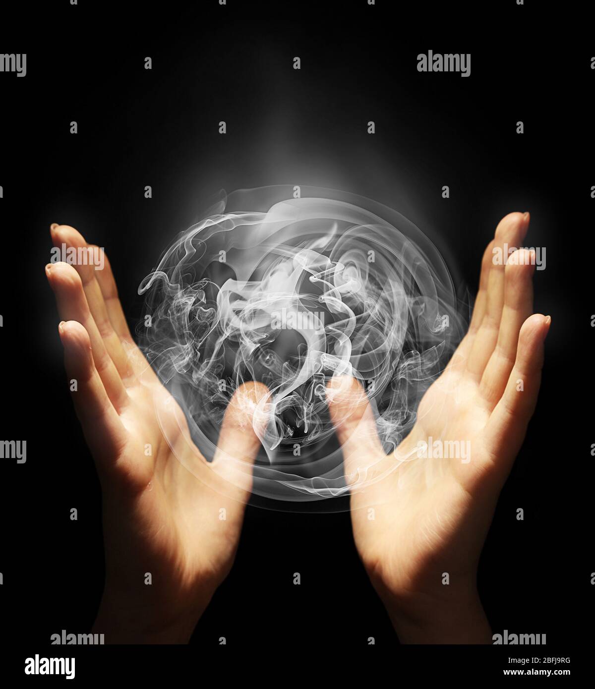 Hands with sphere-shaped smoke isolated on black Stock Photo - Alamy