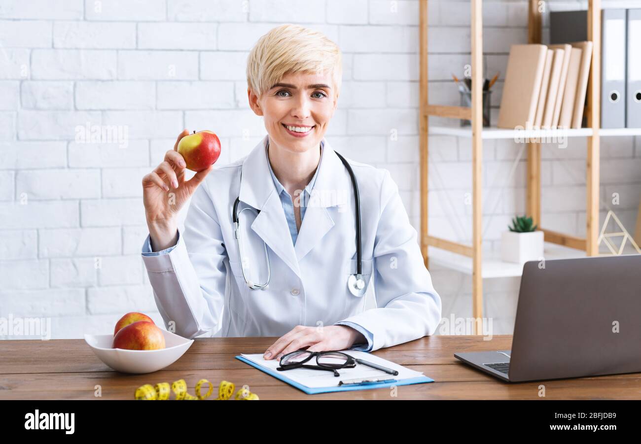 Nutritionist doctor in office at table with apple Stock Photo