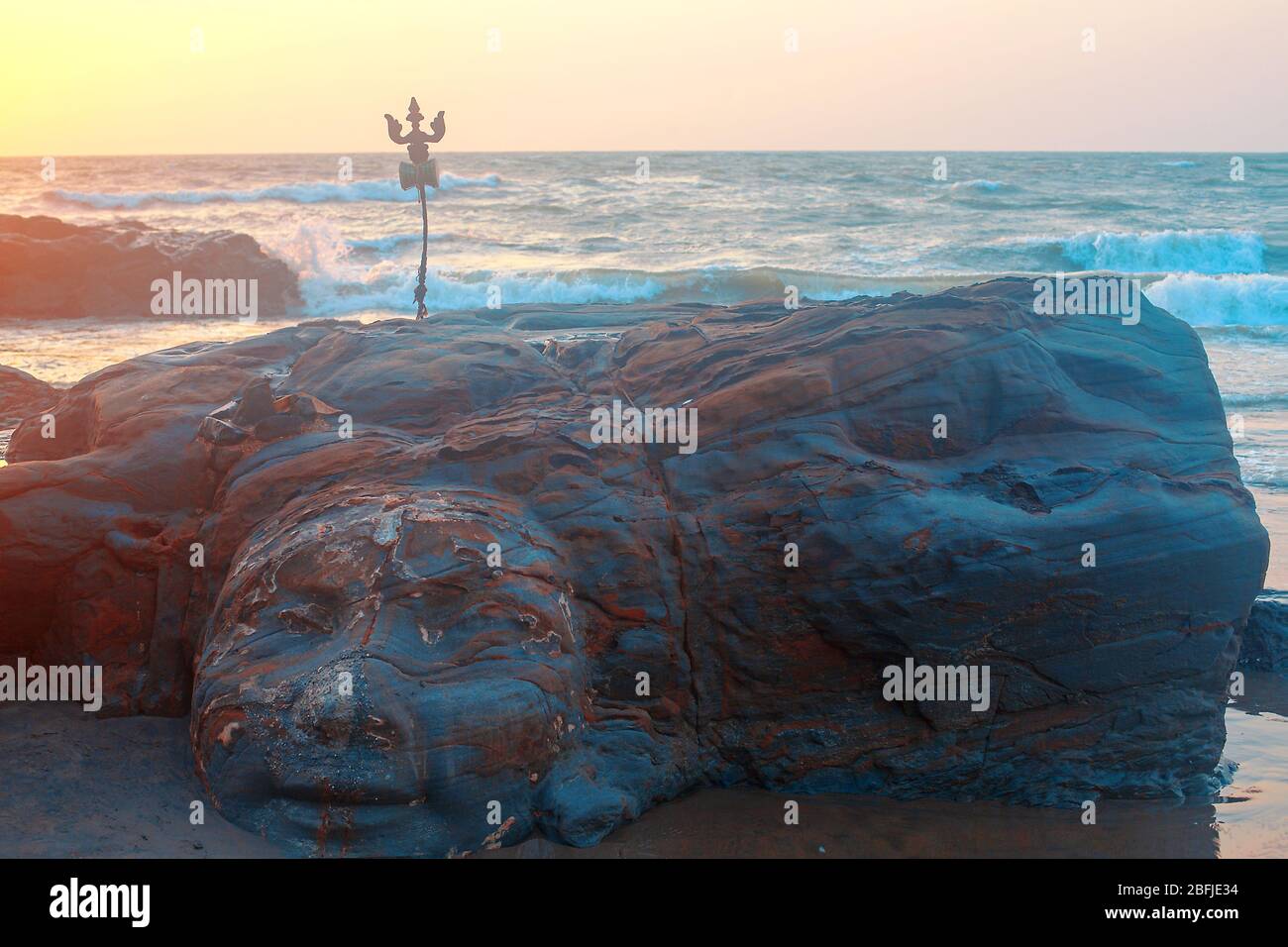 Shiva Face Rock Carving and Trident totem on Vagator Beach, Goa, India. Beautiful sunset background. Northernmost beach of Bardez Taluka in Goa. Oppos Stock Photo