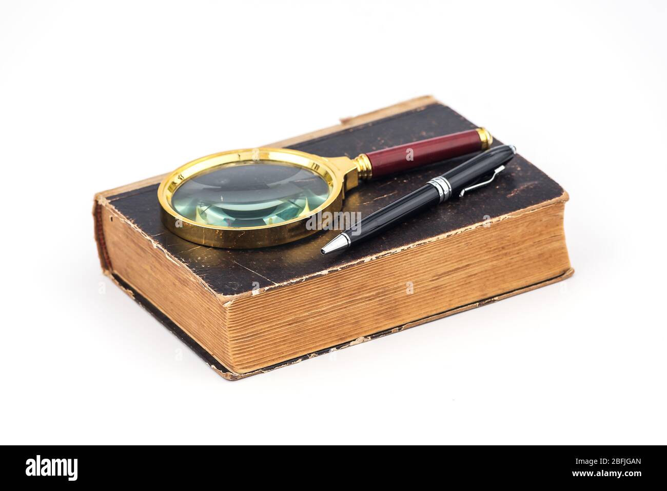 Old book with magnifying glass and a pen on a white background ...