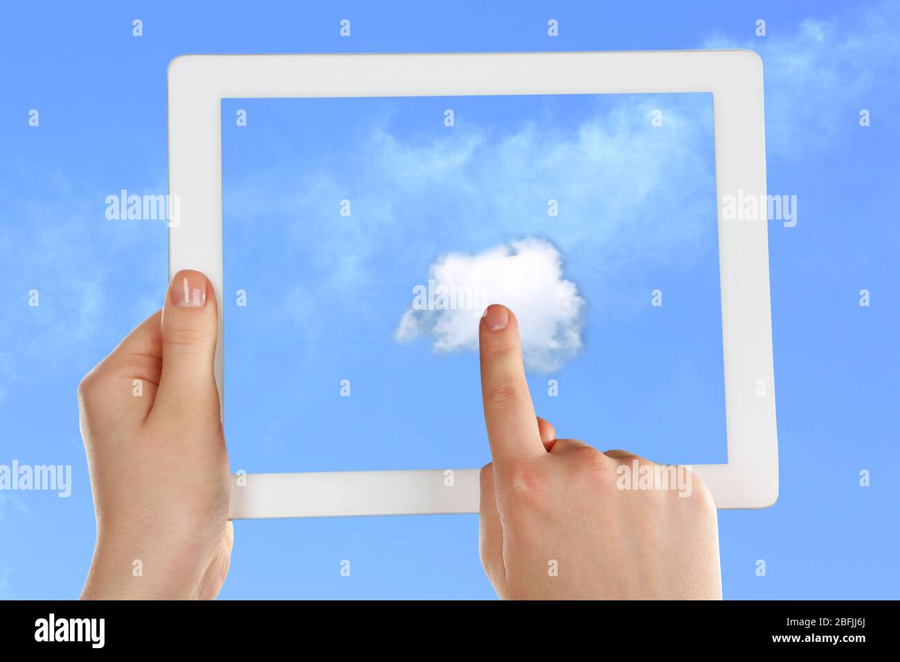Hand touching cloud on tablet on sky background Stock Photo