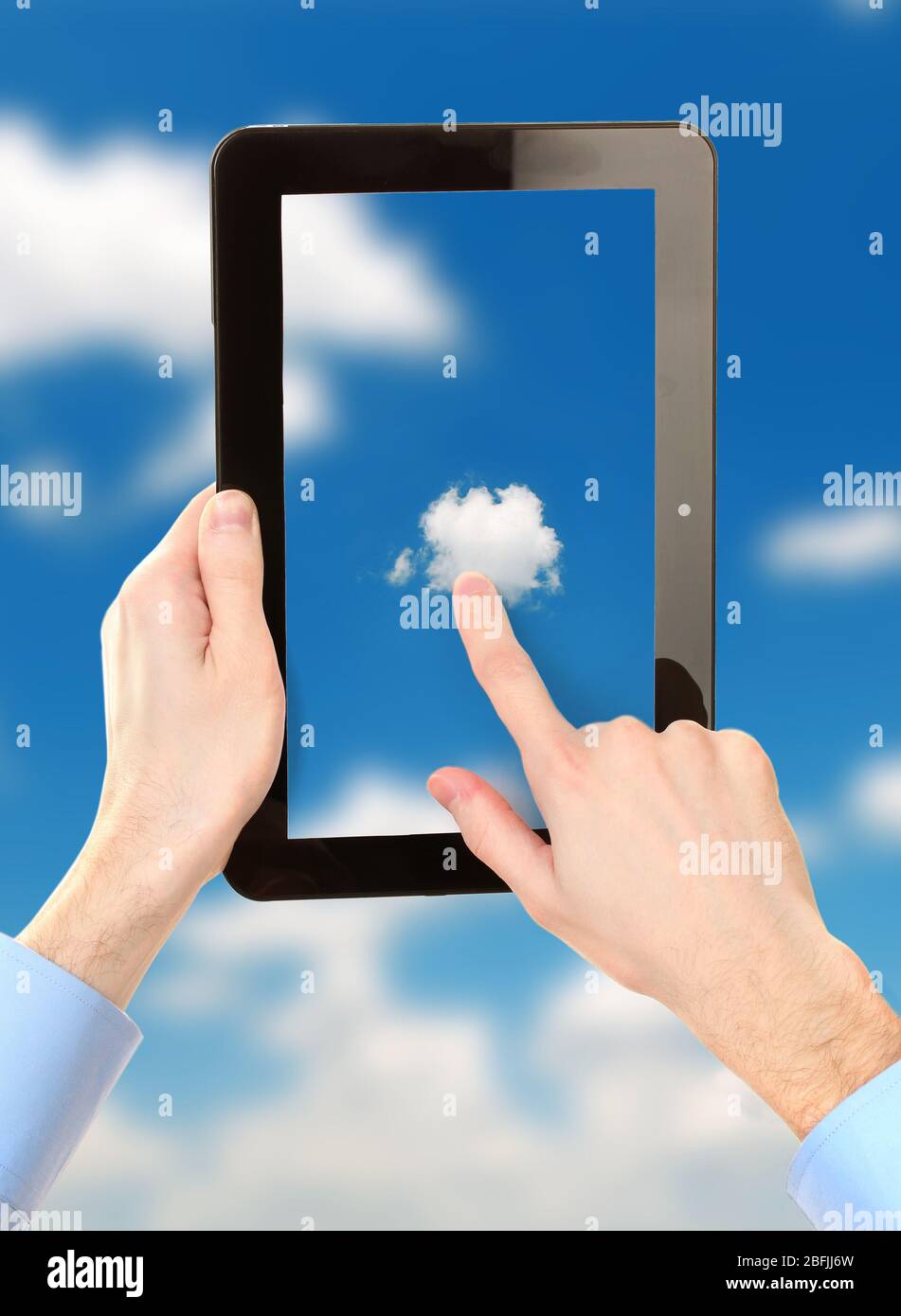 Hand touching cloud on tablet on sky background Stock Photo
