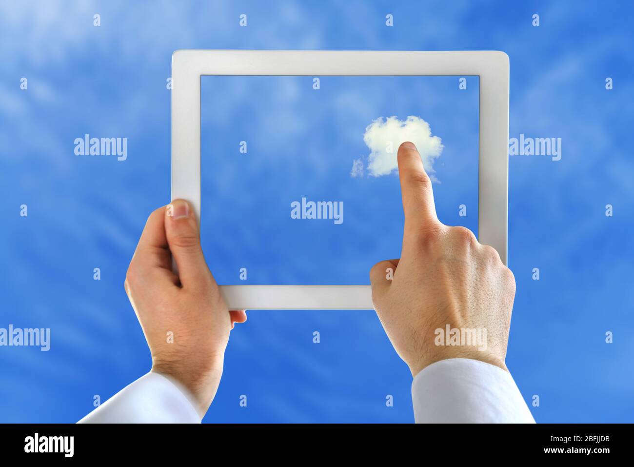 Hand touching cloud on tablet on sky background Stock Photo