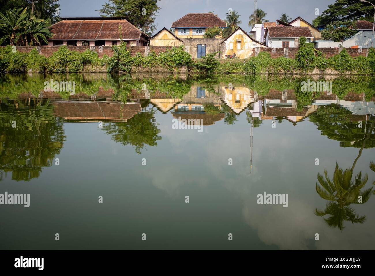Old houses reflecting on a pond, with no people, in the historical district of Kochi, Kerala, India Stock Photo