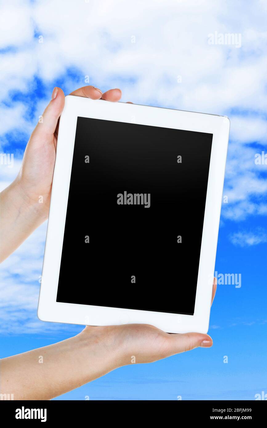 Hands holding tablet PC on sky background Stock Photo