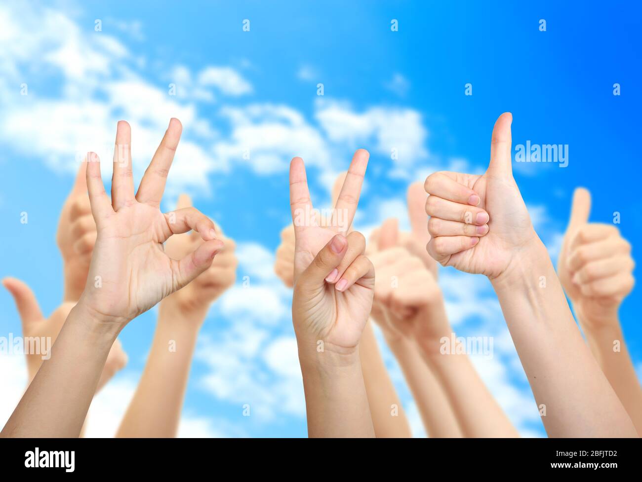 Young people's hands on sky background Stock Photo - Alamy