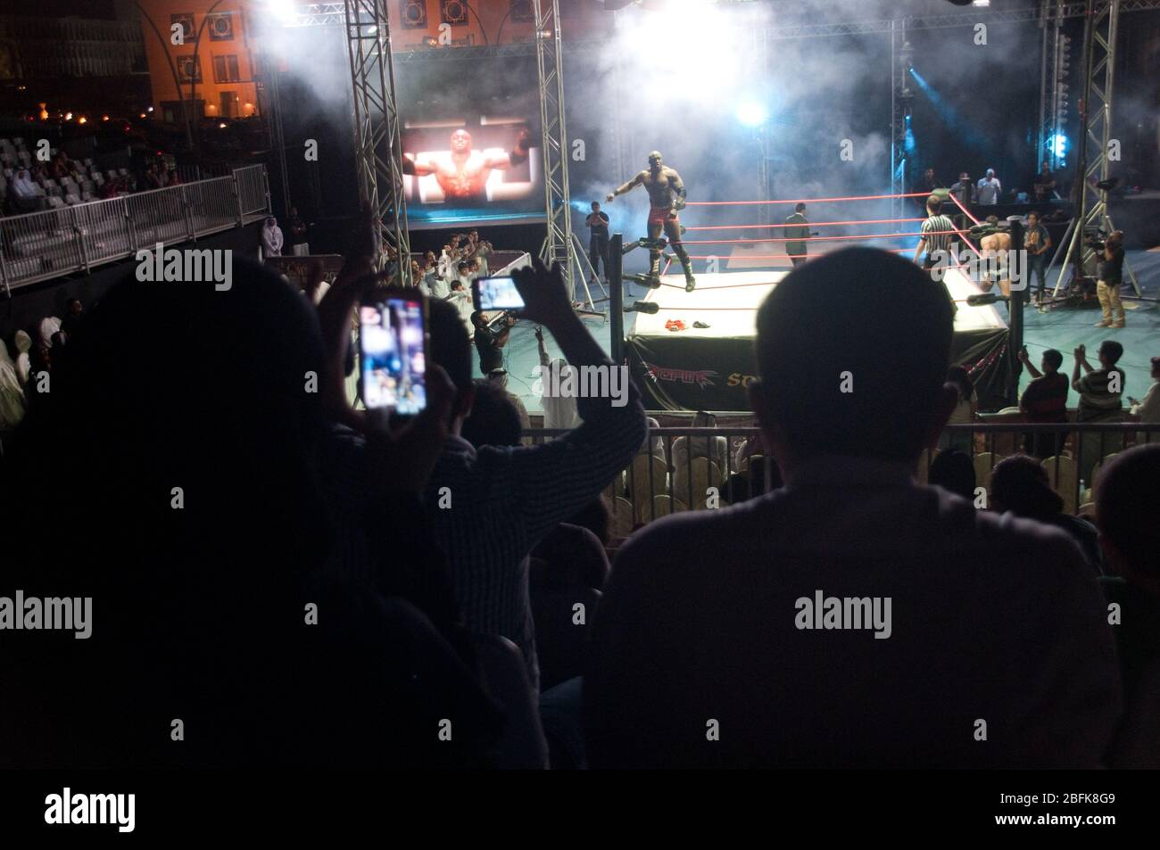An audience on its feet cheering at a live outdoor pro wrestling match in Doha, Qatar. Stock Photo