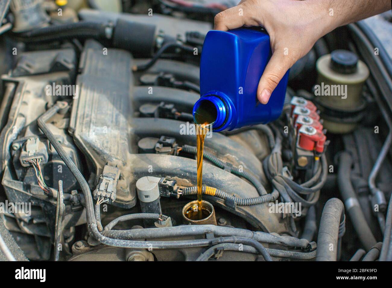 Close up photo of a male hand pouring an oil into a car engine Stock