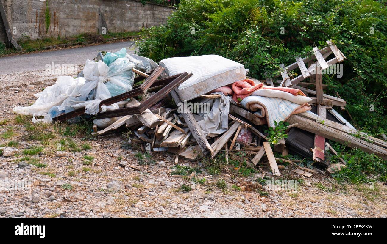Garbage dumped boards, mattress, comforter, plastic bags full of