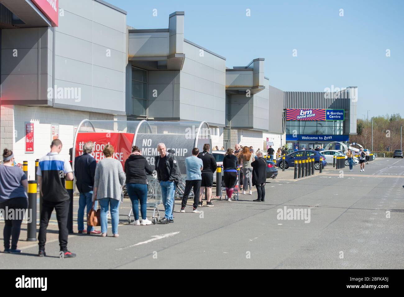 Glasgow, UK. 19th Apr, 2020. Pictured: Long lines of people wait in queues outside of B&M stores during a hot and sunny weekend under the Coronavirus (COVID-19) lockdown. Social distancing can be seen as people queue. To date in the UK confirmed cases of infected people are 120,067 with 16,060 deaths. Credit: Colin Fisher/Alamy Live News Stock Photo