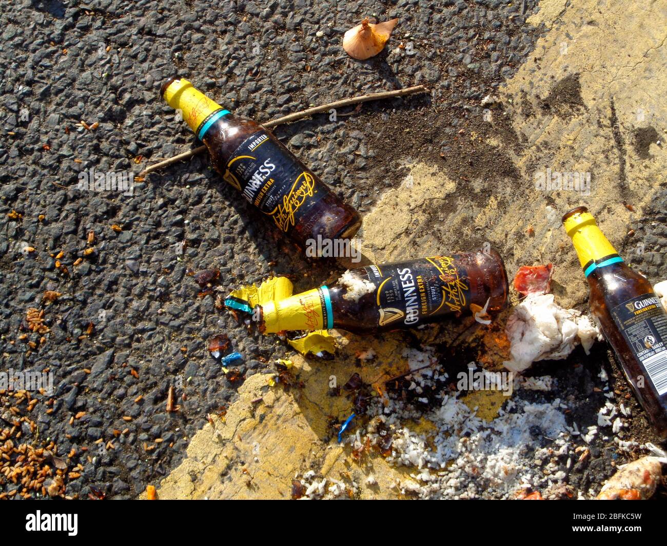Beer bottles casually discarded on the road next to a yellow parking