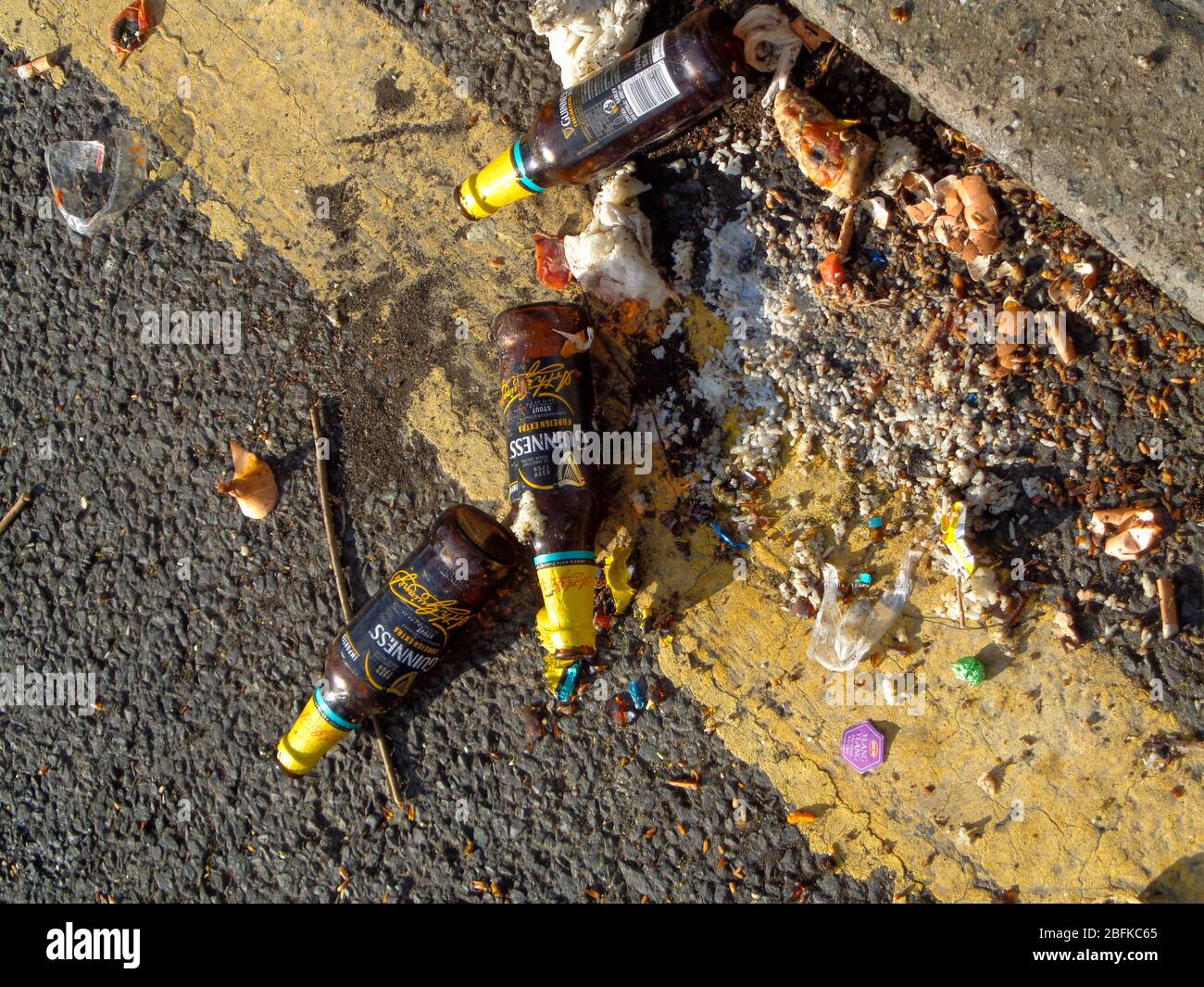 Beer bottles casually discarded on the road next to a yellow parking