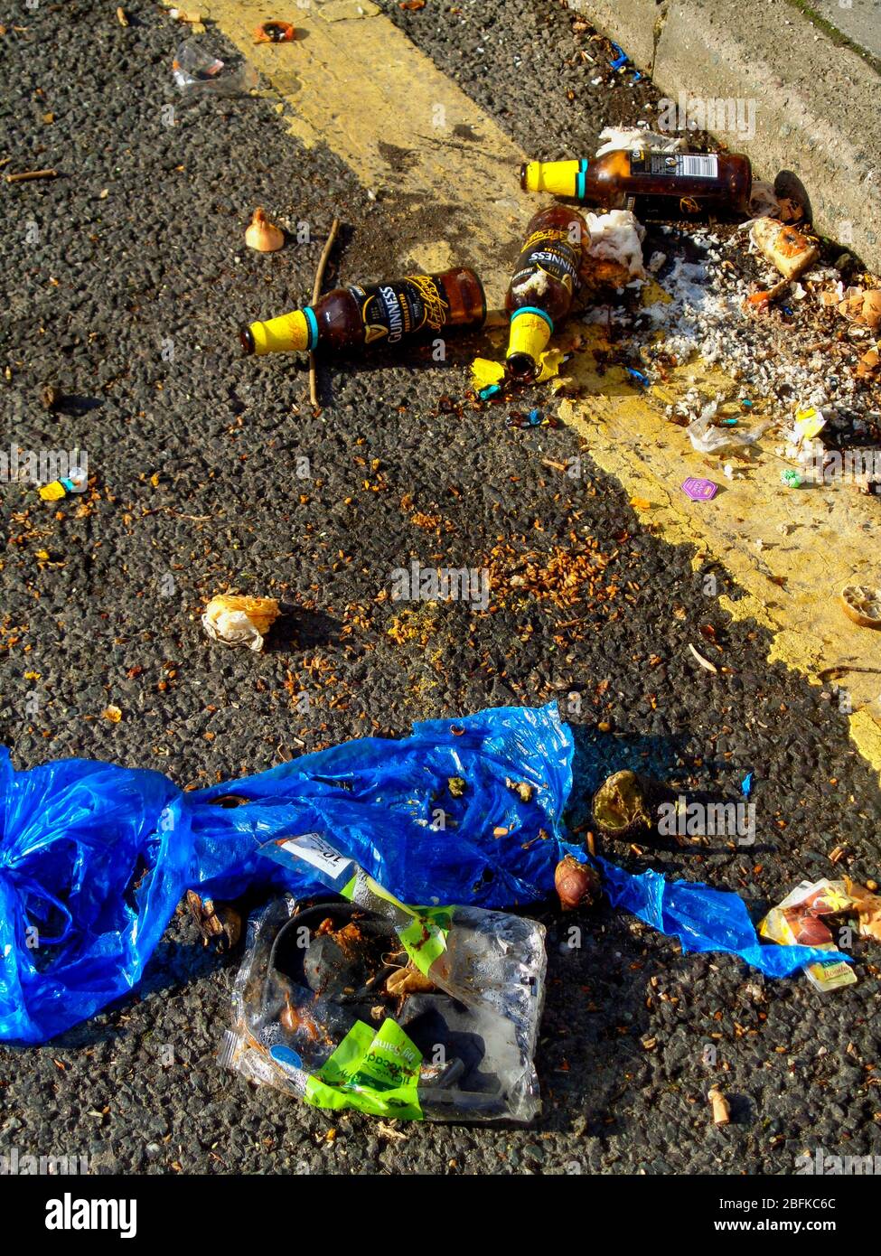 Beer bottles casually discarded on the road next to a yellow parking
