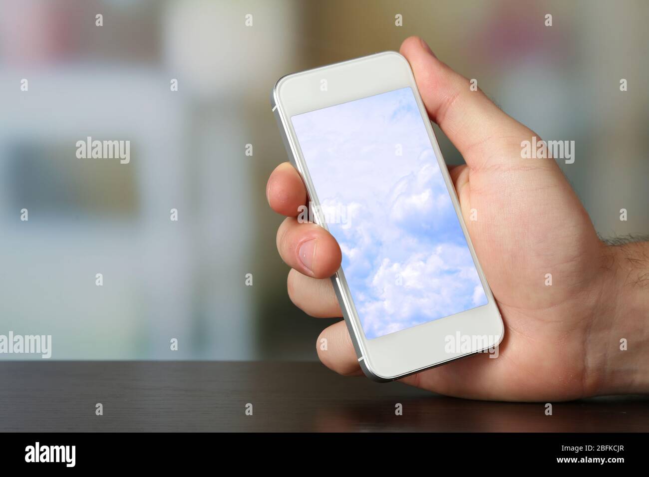 Hand holding mobile smart phone with sky in screen. Cloud computing ...